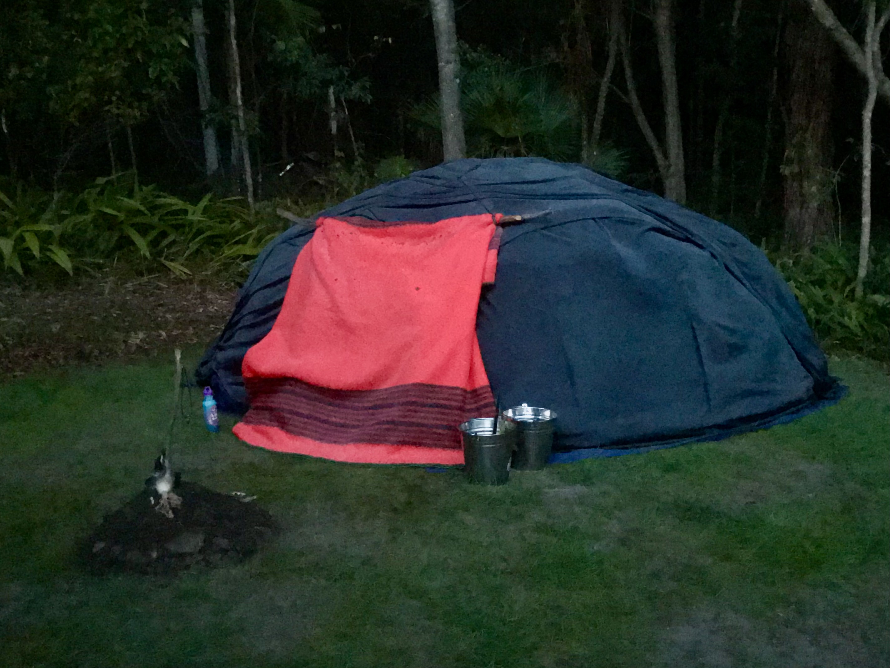 Covered Lodge at Valla, with a red entrance cloth among trees.